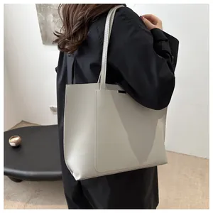 Détail du grand sac cabas gris clair en similicuir avec poche frontale et fines bandoulières