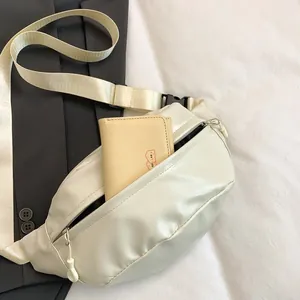 Close-up of cream PU leather waist bag with glossy crinkle texture and adjustable strap