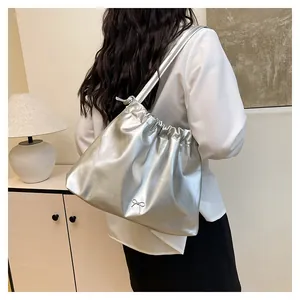 Silver metallic drawstring tote bag with elegant bow detail shown on a female model