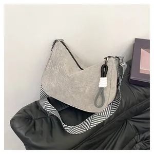 Detail of grey corduroy crescent bag with geometric strap and decorative knot charm