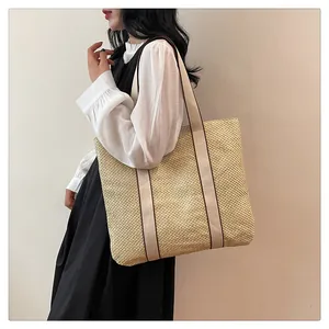 Detail of a large capacity straw tote bag with canvas shoulder straps and woven texture