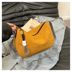 Detail of ginger corduroy hobo bag with striped strap on denim jacket backdrop