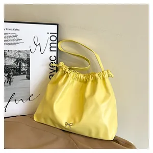 Close-up of vibrant yellow pleated tote bag with drawstring closure and silver bow detail
