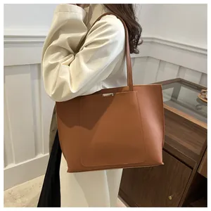 Détail d'un grand sac cabas marron caramel en cuir mat avec boucle métallique décorative