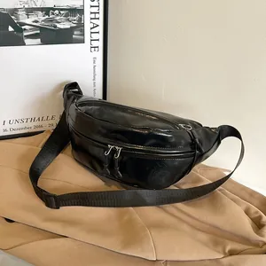Detail view of black glossy waist bag with silver zippers on a beige trench coat
