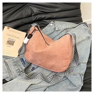 Detail of pink corduroy half-moon bag with woven strap on denim jacket background