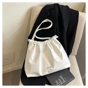 Detailed shot of white pleated tote bag with silver bow on a stylish chair