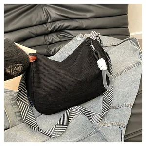 Detail of black corduroy shoulder bag with textured stripes and white knot charm