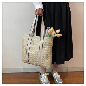 Close-up of beige woven straw tote bag with brown trim straps and yellow tulips