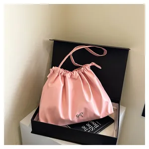 Detail of pink pleated bucket bag featuring a silver bow buckle and drawstring closure