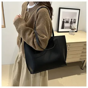 Vue latérale d'un grand sac cabas noir minimaliste porté par un mannequin de mode