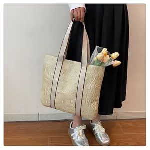 Detail showing natural straw weave texture and white canvas handles of large tote bag