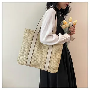 Detail of hand-woven straw tote bag with wide fabric straps and natural woven texture