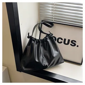 Detail of black pleated tote bag with a small silver metallic butterfly bow buckle