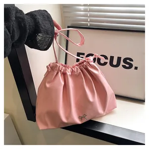 Macro detail of pink pleated drawstring bag with decorative metal bow accent