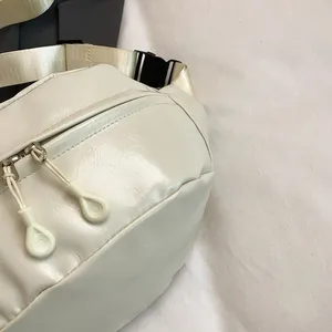 Close-up of creamy white PU leather waist bag featuring dual zippers and durable nylon strap
