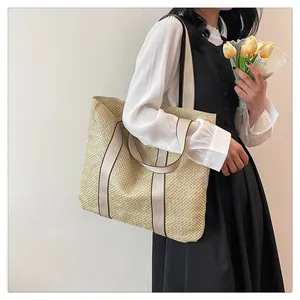 Detail view of woven straw tote bag texture and white fabric shoulder straps for women