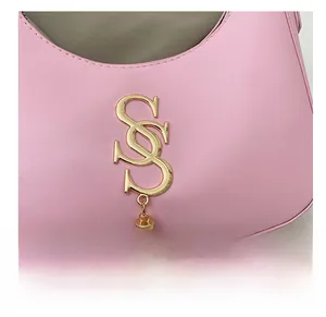 Gros plan du sac croissant rose avec logo doré et pompon métallique élégant