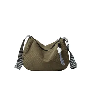 Army green corduroy crossbody pillow bag with striped strap on a white background