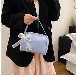 Detailansicht hellviolette Handtasche mit eleganter weißer Spitzenschleife und Perlen