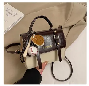 Detail of vintage crossbody bag with baseball charm and gold buckle accents