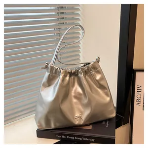 Detail shot of a silver metallic drawstring bag with a delicate metal bow accent