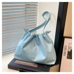 Detail view of light blue pleated tote bag with a small silver metallic bow accessory