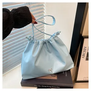 Macro shot of light blue pleated tote bag with a silver bow detail and drawstring closure