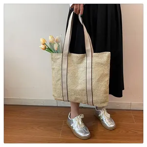 Detail of a beige woven straw tote bag featuring contrast stitching and large capacity