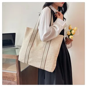Detail of handwoven cream straw tote bag with brown canvas straps and fine texture