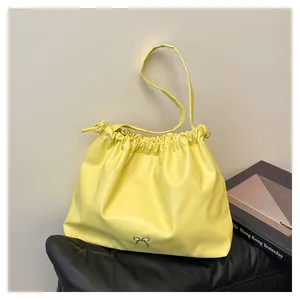Detailed view of yellow gathered shoulder bag with drawstrings and a silver bow