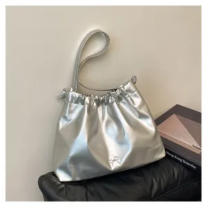 Detail of silver metallic drawstring tote bag featuring a decorative bow and pleated texture