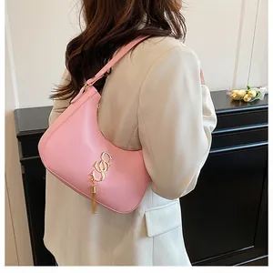 Détail du sac hobo rose avec franges dorées et pompon sur un blazer élégant