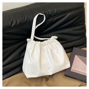 Detailed view of the white pleated underarm bag featuring a silver bow decoration
