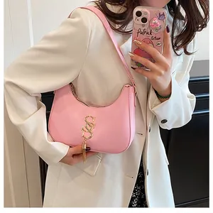 Sac sous le bras rose en demi-lune avec logo S doré et franges sur blazer blanc