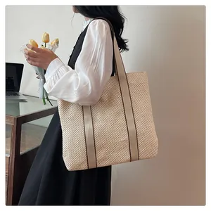 Detail of a large woven straw tote bag with shoulder strap in an elegant office setting