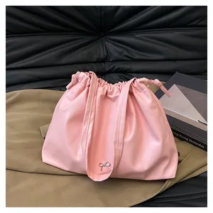 Detail of pink pleated cloud bag with metallic bow charm and drawstring closure