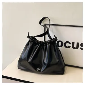 Close-up of black ruched PU leather texture with a silver metal bow accent