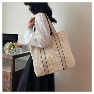 Side view of large woven straw tote bag with canvas straps on a female model