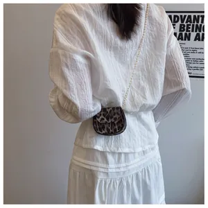 Tragefoto einer Mini-Satteltasche mit Leopardenmuster und goldener Kette am Model