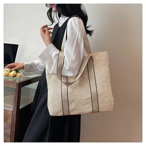 Detail of a beige woven tote bag showing the texture and brown-trimmed fabric straps