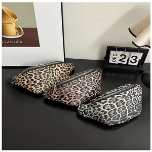 Détail de trois sacs banane à motif léopard en marron, rose et gris sur un bureau en bois