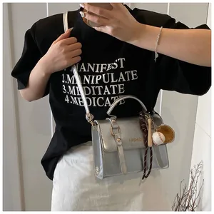 Close-up of silver metallic crossbody bag with FASHION logo and baseball keychain charm