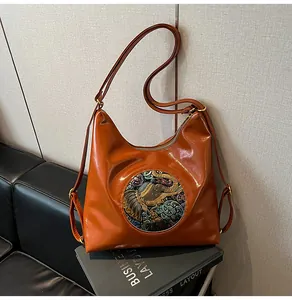 Detail of vintage brown tote bag with colorful elephant relief patch and glossy texture