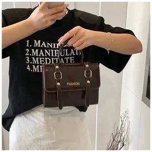 Detail view of dark brown glossy leather handbag with gold metal hardware and fashion text