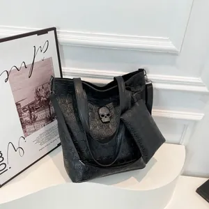 Schwarze Shopper-Tasche mit Totenkopf-Prägung und Metall-Detail in elegantem Studio-Ambiente
