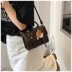 Detail view of a vintage dark brown leather crossbody bag with a baseball glove charm