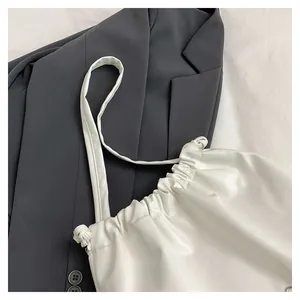 Close-up of white pleated tote bag showing premium PU leather texture on grey blazer
