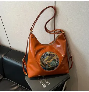 Close-up of orange-brown Hobo bag with ethnic elephant embroidery on leather texture
