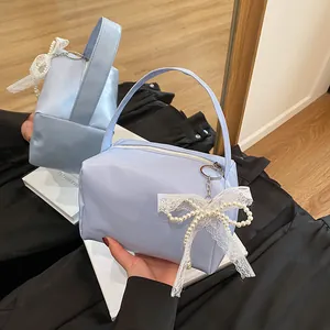 Elegant light blue leather underarm bag with a white lace pearl bow charm detail